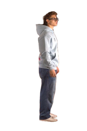 Person wearing a light gray hoodie and dark blue jeans standing on a brown leather couch.