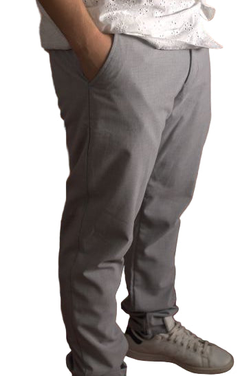 Person wearing gray pants and white sneakers on a brown leather couch.