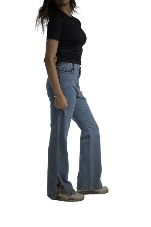 Person wearing blue jeans and a black top on a plain background