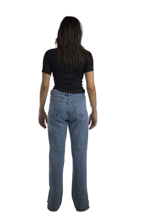 Person wearing blue jeans and a black top on a plain background