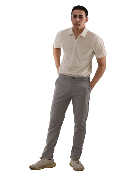 Man wearing a white shirt and gray pants standing on a light-colored floor.