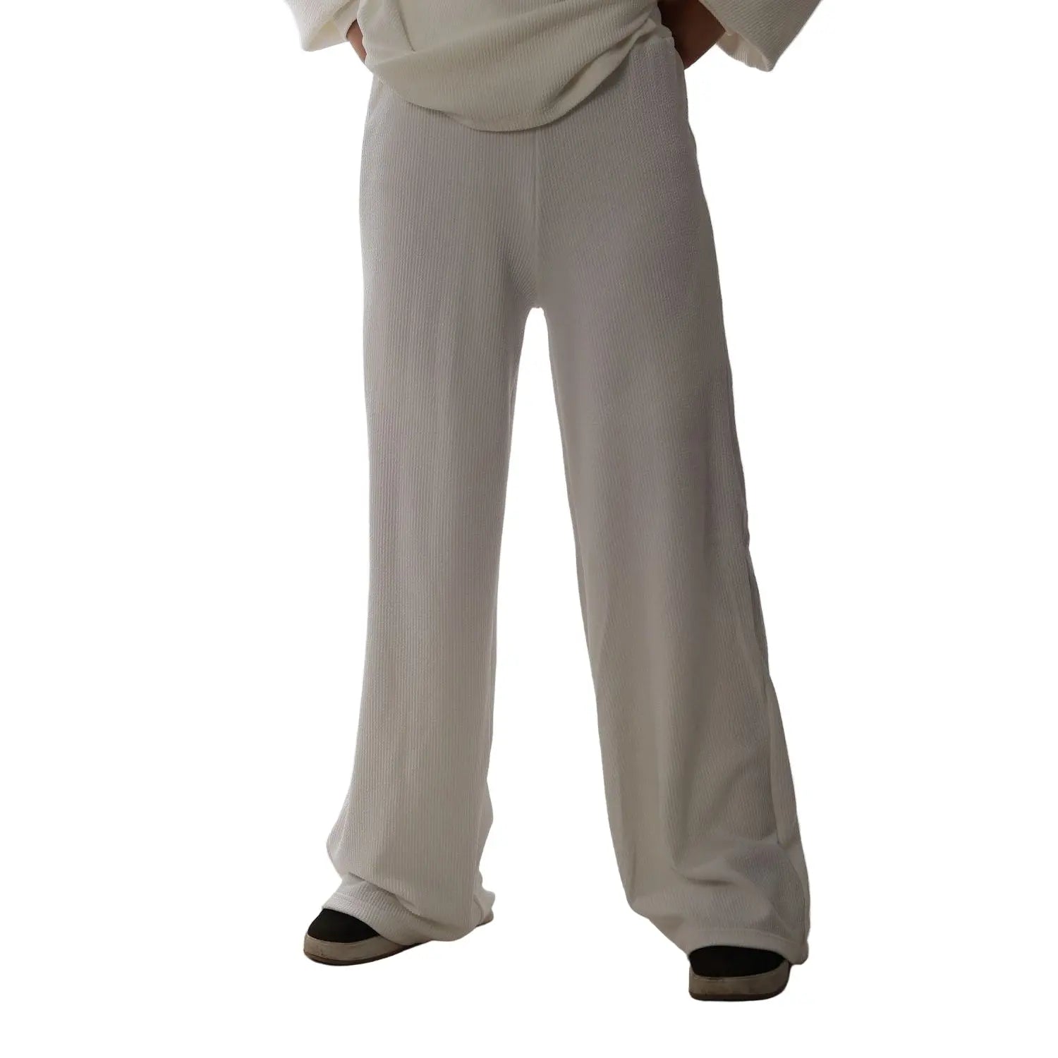 Person wearing white pants and black shoes on a plain background